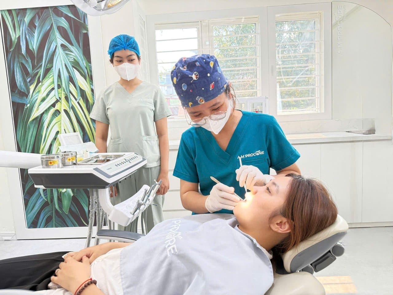 Two clinicians treating a patient in a bright AM Procare operatory — team-based clinical care